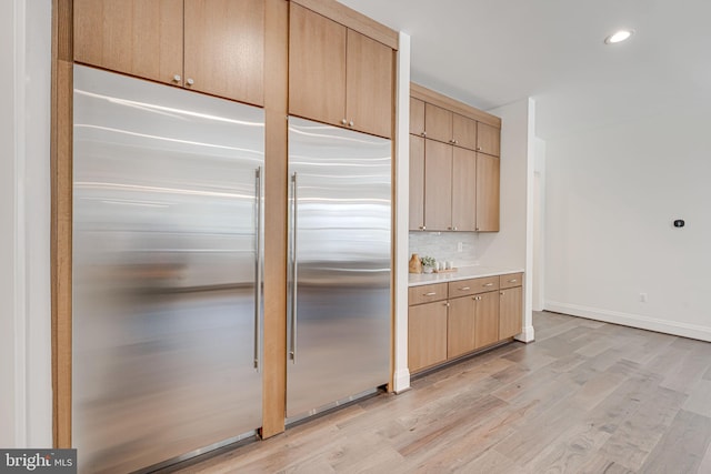 kitchen featuring tasteful backsplash, stainless steel built in fridge, light brown cabinets, and light hardwood / wood-style flooring