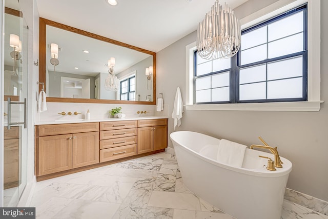 bathroom with a notable chandelier, vanity, and a tub