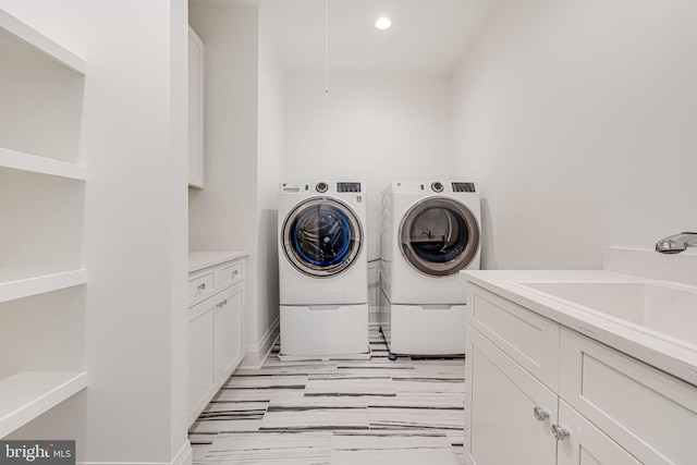 washroom featuring cabinets, sink, and washer and clothes dryer