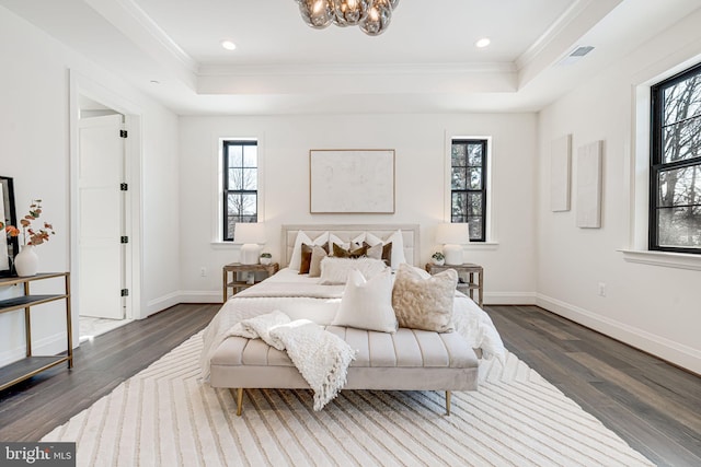 bedroom with dark wood-type flooring, ornamental molding, and a tray ceiling