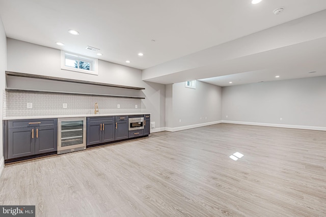 bar with gray cabinetry, beverage cooler, light wood-type flooring, and decorative backsplash