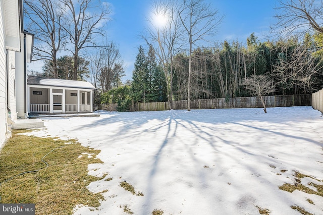 yard layered in snow featuring a sunroom