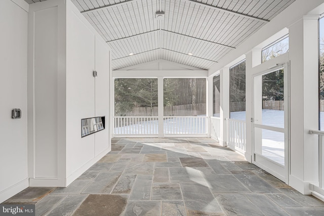 unfurnished sunroom featuring lofted ceiling and plenty of natural light