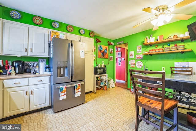 kitchen featuring ceiling fan, stainless steel fridge, and white cabinets