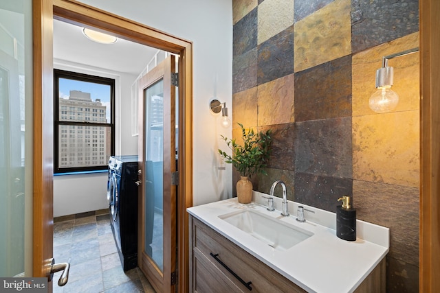 bathroom with vanity, separate washer and dryer, and tile walls