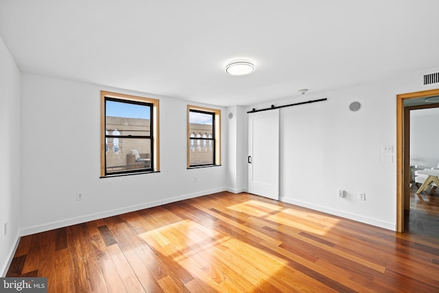 empty room with hardwood / wood-style flooring and a barn door