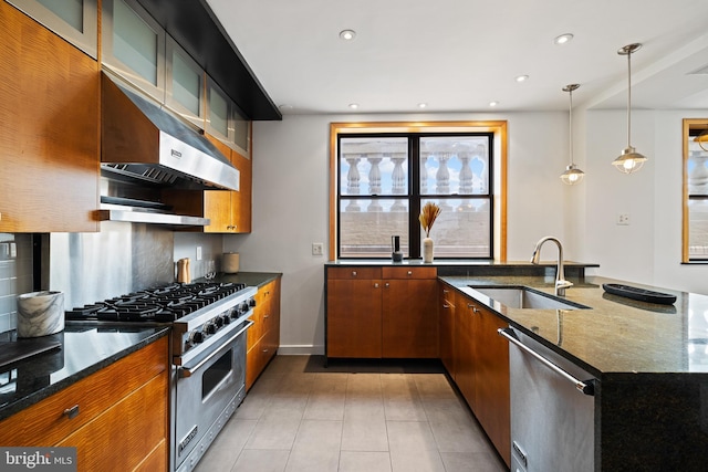 kitchen featuring sink, dark stone countertops, decorative backsplash, hanging light fixtures, and stainless steel appliances