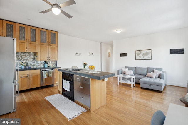 kitchen featuring appliances with stainless steel finishes, a center island, light wood-type flooring, and backsplash