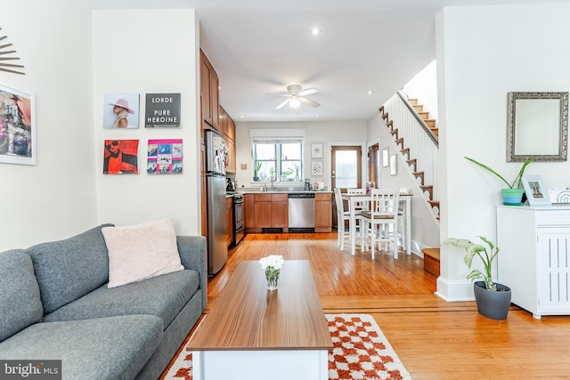 living room with ceiling fan, sink, and light hardwood / wood-style flooring