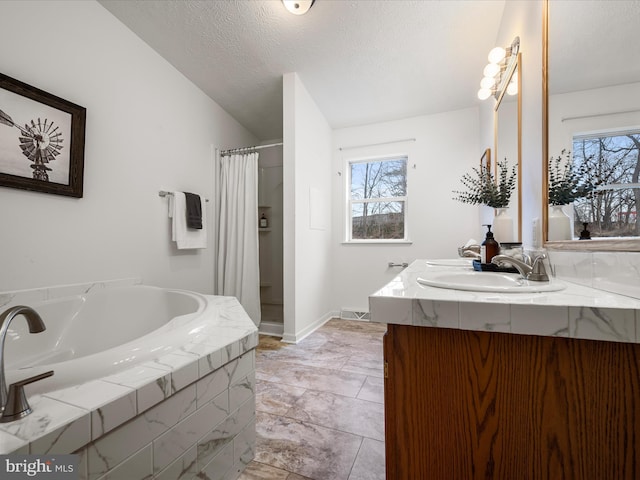 bathroom featuring vanity, lofted ceiling, a healthy amount of sunlight, and a textured ceiling