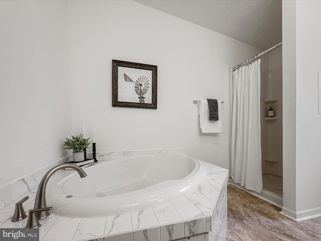 bathroom featuring shower with separate bathtub and a textured ceiling