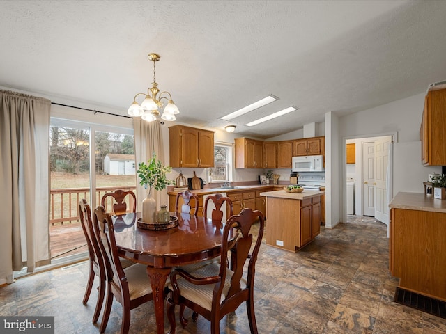 dining room featuring an inviting chandelier, lofted ceiling, a healthy amount of sunlight, and a textured ceiling