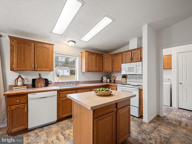 kitchen with washer / dryer, sink, a center island, vaulted ceiling, and white appliances