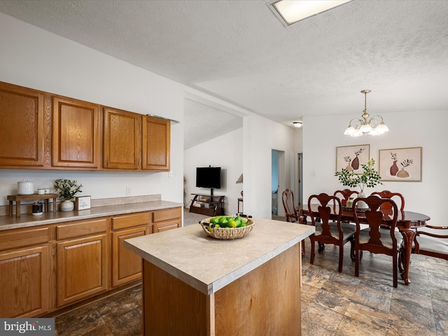 kitchen with pendant lighting, a center island, a textured ceiling, and an inviting chandelier