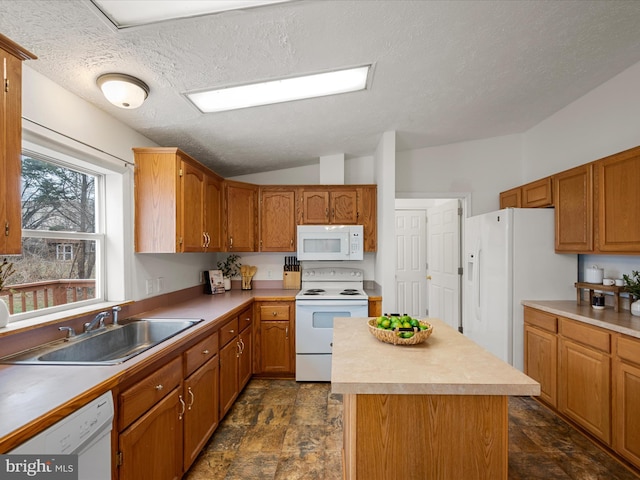 kitchen with lofted ceiling, sink, a textured ceiling, a kitchen island, and white appliances