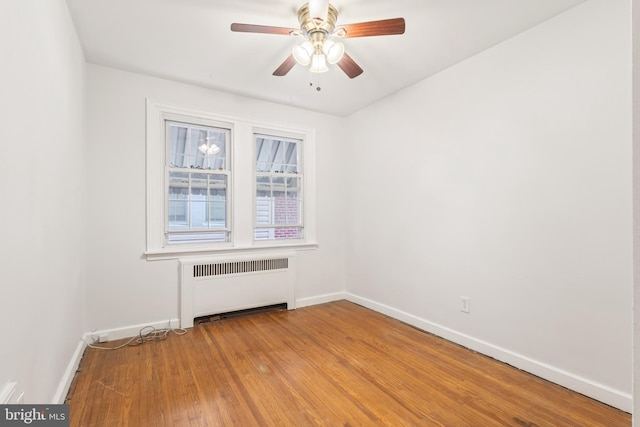 unfurnished room with radiator, wood-type flooring, and ceiling fan