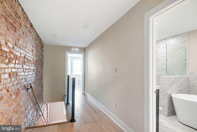 hall featuring light hardwood / wood-style flooring and tile walls