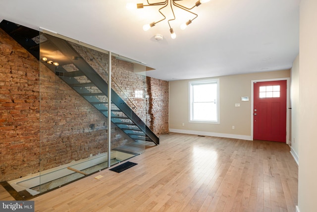 entryway with brick wall and hardwood / wood-style floors