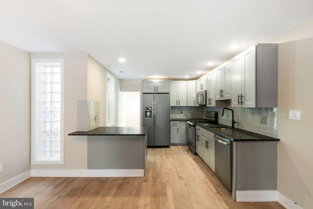 kitchen featuring light hardwood / wood-style floors, appliances with stainless steel finishes, gray cabinetry, sink, and kitchen peninsula