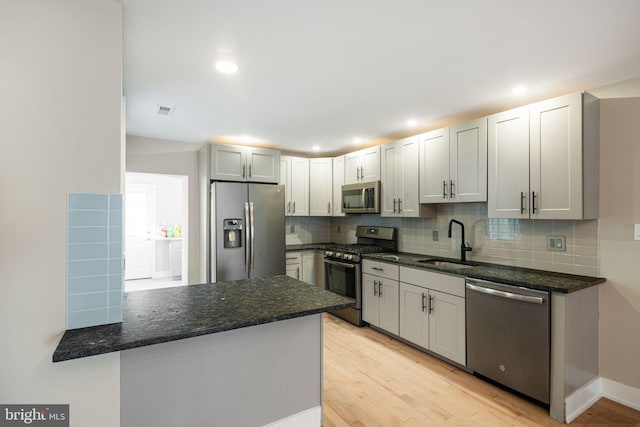 kitchen with sink, light hardwood / wood-style flooring, kitchen peninsula, and stainless steel appliances