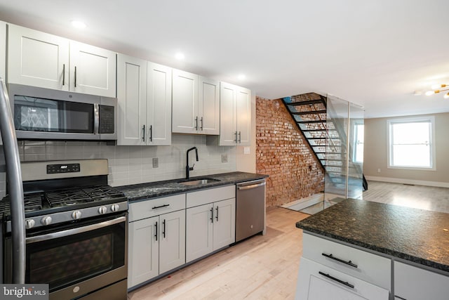 kitchen with sink, white cabinets, light hardwood / wood-style flooring, and stainless steel appliances