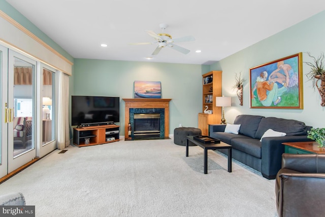 living room with ceiling fan, a premium fireplace, and light carpet