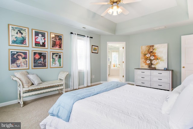 carpeted bedroom with ceiling fan, connected bathroom, and a raised ceiling