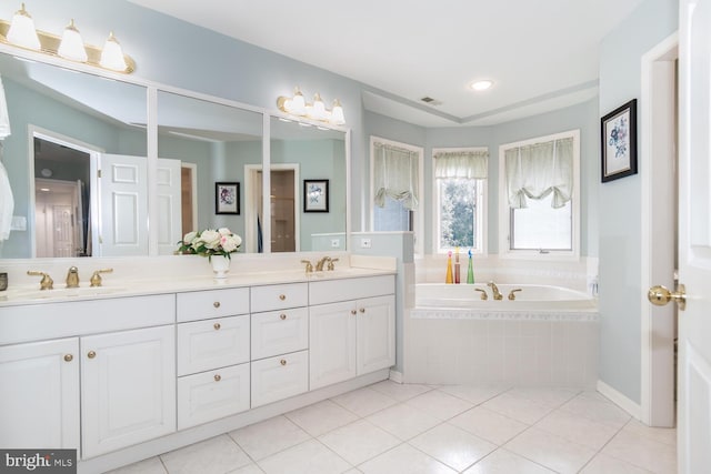 bathroom with tile patterned flooring, vanity, and tiled tub