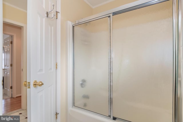 bathroom with crown molding and bath / shower combo with glass door