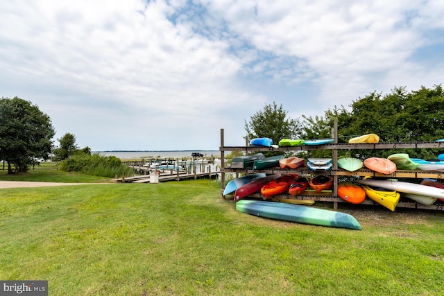 view of dock with a water view and a yard