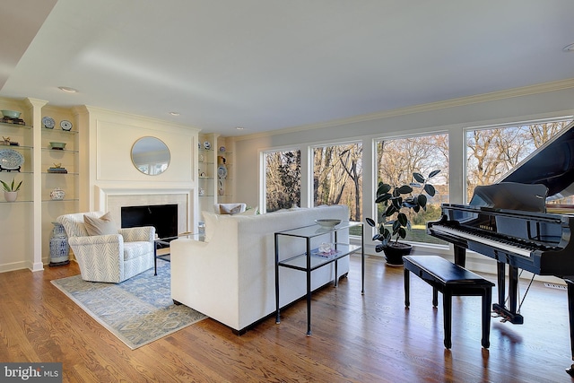 living room featuring hardwood / wood-style floors, built in shelves, and ornamental molding