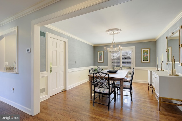 dining space featuring hardwood / wood-style flooring, ornamental molding, and a notable chandelier