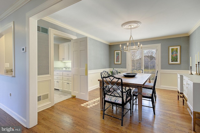 dining room with a notable chandelier, light hardwood / wood-style flooring, and ornamental molding