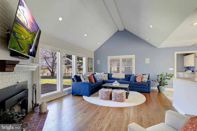 living room with hardwood / wood-style floors, beam ceiling, a fireplace, and high vaulted ceiling