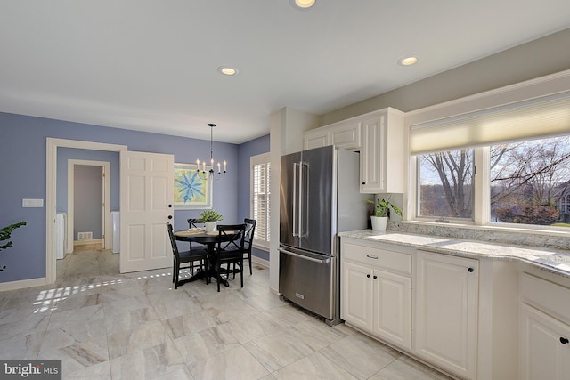 kitchen featuring white cabinetry, light stone countertops, plenty of natural light, and high quality fridge