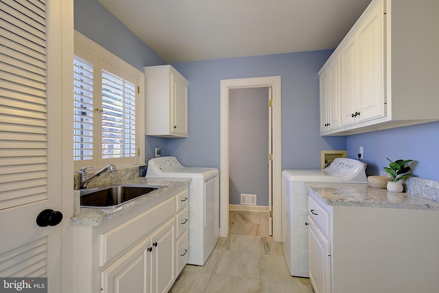 laundry area with sink, washing machine and dryer, and cabinets