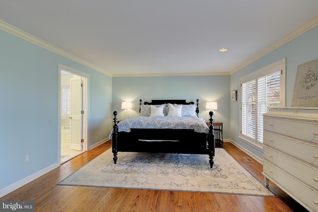 bedroom with hardwood / wood-style flooring, crown molding, and ensuite bath