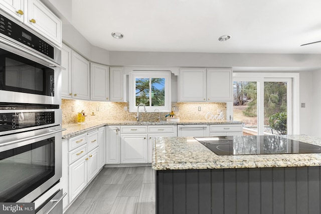 kitchen featuring white cabinetry, light stone countertops, and black electric cooktop