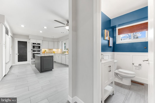 bathroom with ceiling fan, decorative backsplash, sink, and toilet