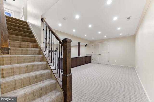 stairs with crown molding and carpet