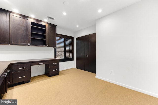 unfurnished office featuring built in desk and light colored carpet