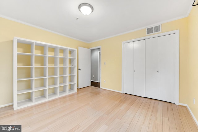 unfurnished bedroom with ornamental molding, light hardwood / wood-style floors, and a closet