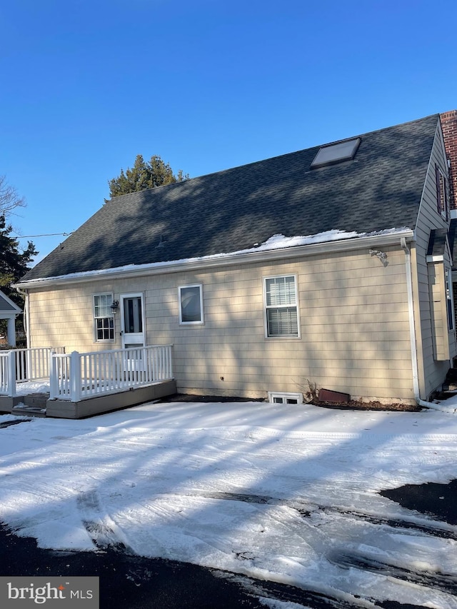 snow covered house with a wooden deck