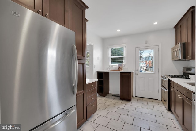 kitchen featuring light tile patterned flooring, appliances with stainless steel finishes, and dark brown cabinetry