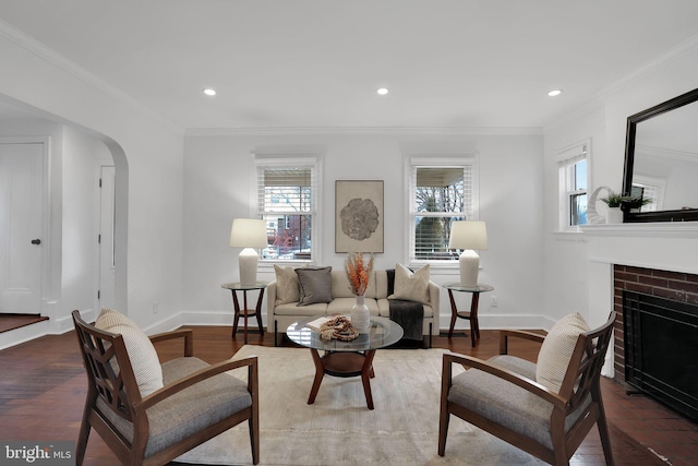 living room with crown molding, a brick fireplace, and dark wood-type flooring