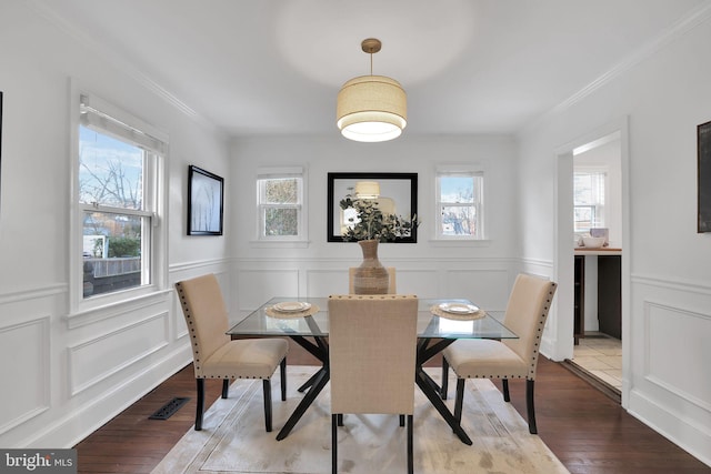 dining room featuring wood-type flooring, a wealth of natural light, and crown molding