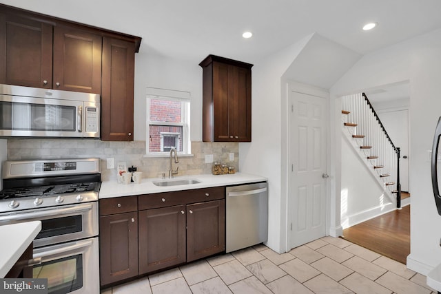 kitchen with dark brown cabinetry, stainless steel appliances, sink, and backsplash