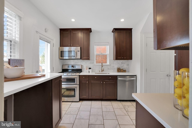 kitchen with stainless steel appliances, tasteful backsplash, sink, and dark brown cabinetry