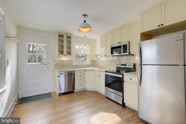 kitchen with plenty of natural light, appliances with stainless steel finishes, hanging light fixtures, and backsplash