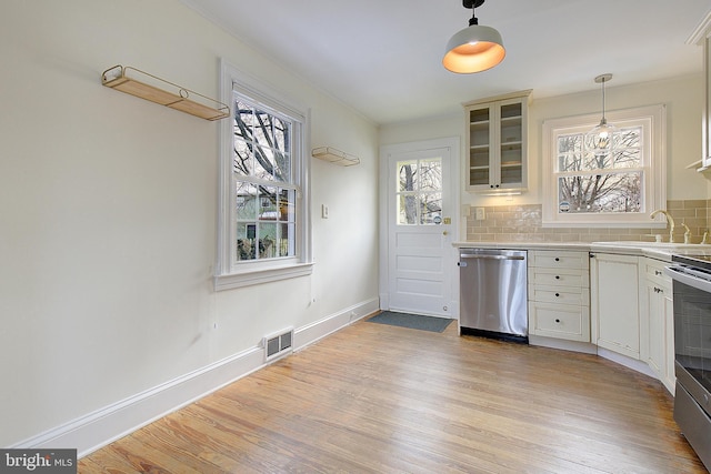 kitchen with pendant lighting, sink, backsplash, light hardwood / wood-style floors, and stainless steel appliances